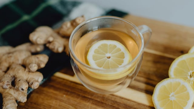 En kop varm ingefærte med citronskive og frisk ingefærrod – en mild drik, der af mange bruges mod kvalme under kræftbehandling.
