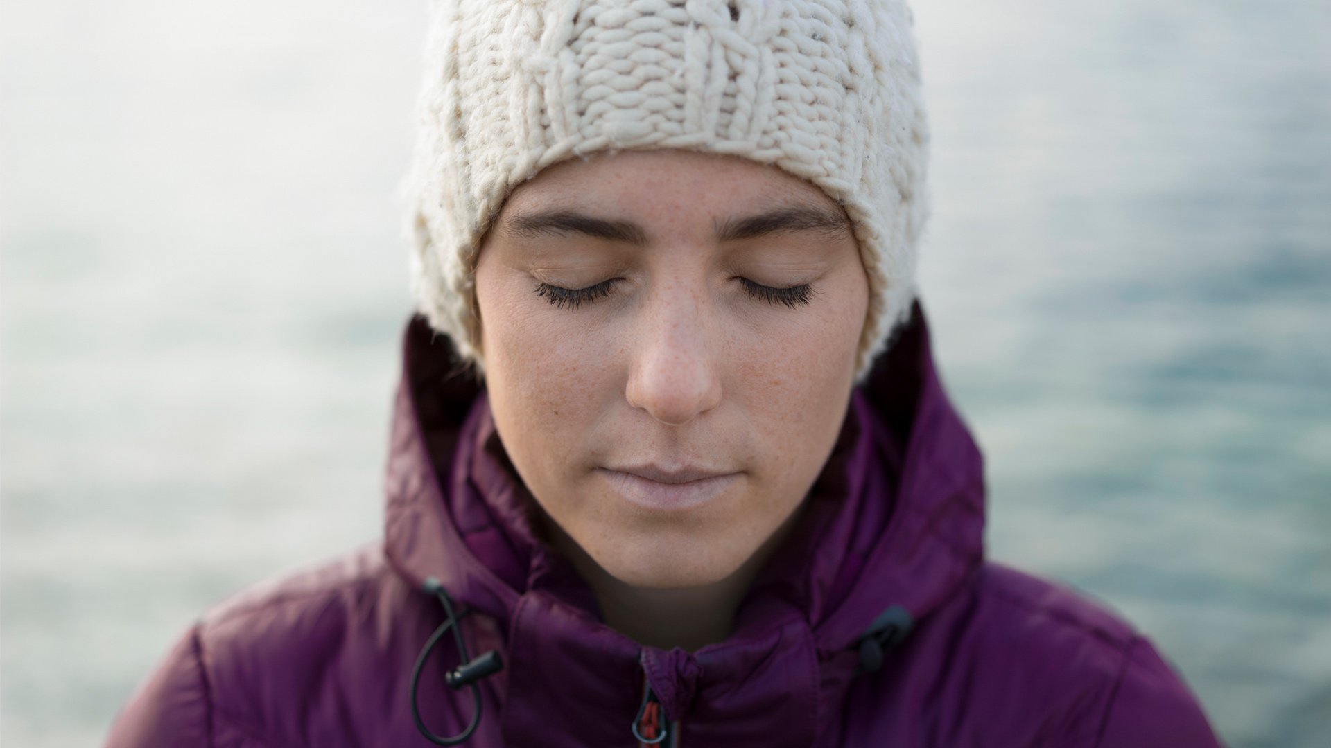 Ung kvinde der enten har Hormonreceptor-positiv brystkræft (HR+), HER2-positiv brystkræft (HER2+) eller triple-negativ brystkræft. Hun står med lukkede øjne og hue ude. Illustrationsfoto