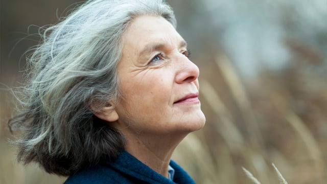 Nærbillede af kvinde med metastatisk brystkræft, der balancerer svære følelser ude i naturen og kigger op i luften. Illustrationsfoto