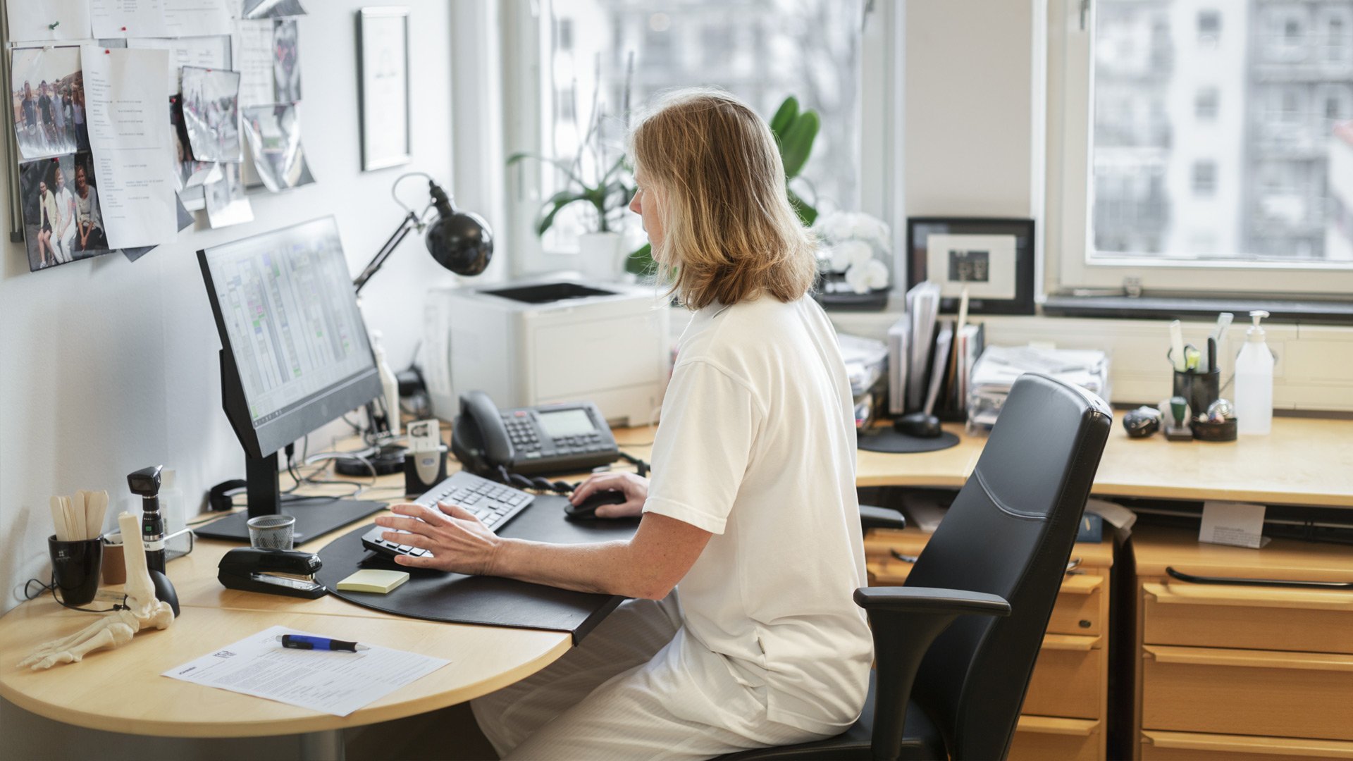 Kvindelig kræftlæge sidder ved kontorpulten og arbejder med metastaserende brystkræft. Illustrationsfoto